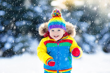 Child playing with snow in winter. Kids outdoors.