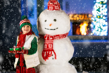 Kids and snowman in garden at Christmas fireplace.
