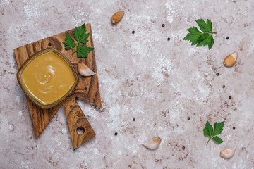 Homemade mustard sauce and ingredients on brown concrete background. Top view