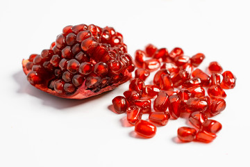 Spoon with ripe pomegranate seeds on a white isolated background.