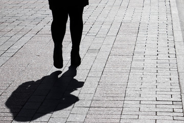Fat woman walking down on a street, black silhouette and shadow on pavement. Concept of overweight, loneliness, parting, human life