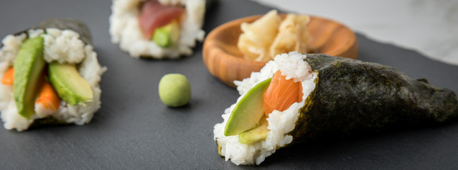 Lachs Fisch, Tunfisch und Surimi Avocado Temaki Sushi, eingelegter Ingwer und Wasabi auf Schiefer Platte und Marmor Hintergrund
