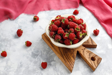 Ripe sweet raspberries in ceramic plate  on grey concrete background. Close up, top view