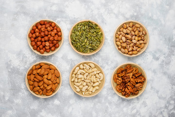 Assortment of nuts in ceramic plates. Cashew, hazelnuts, walnuts, pistachio, pecans, pine nuts, peanut, raisins.top view