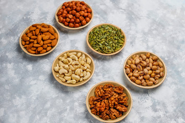 Assortment of nuts in ceramic plates. Cashew, hazelnuts, walnuts, pistachio, pecans, pine nuts, peanut, raisins.top view