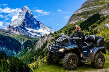A happy woman riding a quad bike near a lake in the mountains Matterhorn, Zermatt © Angelov