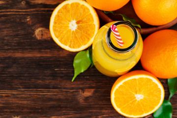 Bottle of orange juice with oranges on wooden table