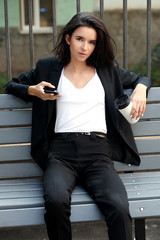 Young happy business woman using smart phone and drinking coffee in street cafe