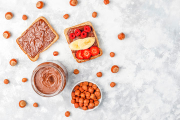 Chocolate spread or nougat cream with hazelnuts in glass jar on concrete background, copy space