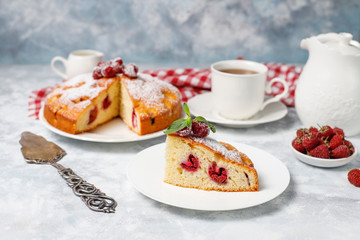 Simple cake with powdered sugar and fresh raspberries on a light background. Summer berry dessert.