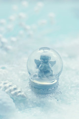 Small snow globe with angel figurine and snow; winter background with copy space