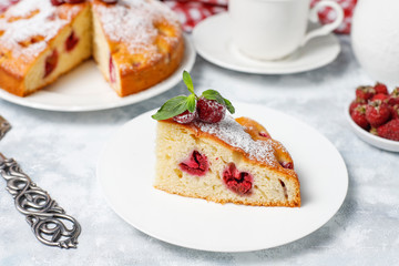 Raspberry cake with powdered sugar and fresh raspberries on a light background. Summer berry dessert.