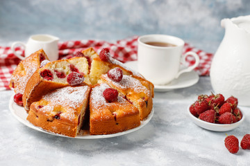 Raspberry cake with powdered sugar and fresh raspberries on a light background. Summer berry dessert.