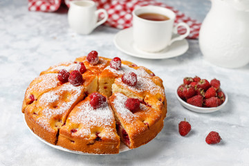 Raspberry cake with powdered sugar and fresh raspberries on a light background. Summer berry dessert.