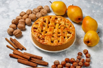 Homemade pear pie with cinnamon and walnuts on light background