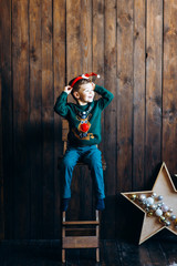 Boy in knitted Christmas sweaters in anticipation of Christmas with Christmas decor. Winter New Year and Christmas mood