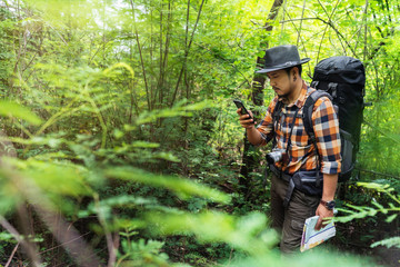 man traveler with backpack using smartphone in the forest © geargodz