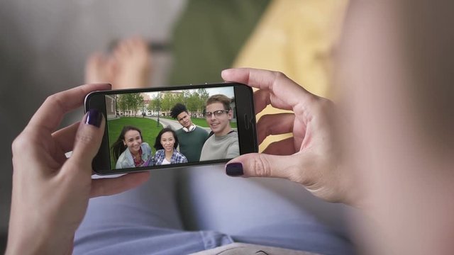 girl talking to friends via skype on her smart phone while lying on sofa. closeup. studens, facetime, internet, video, online, long distance, chatting, friendship concept