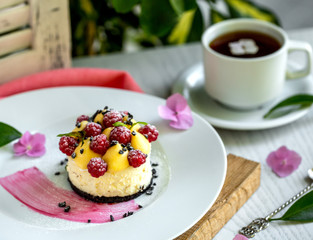 portioned cheesecake garnished with yellow cream and raspberries