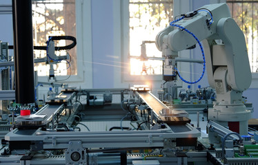 Industry 4.0 concept; artificial intelligence in smart factory prototype. Robot picks up the product from automated car on the manufacturing line. Focus on robotic arm's gripper. Selective focus.