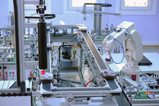 Industry 4.0 concept; artificial intelligence in smart factory prototype. Robot picks up the product from automated car on production line. Focus on robot arm's gripper. Selective focus.
