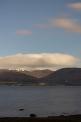 The clouds slowly moving away to show the bright stars shining over Loch Lomond Scotland