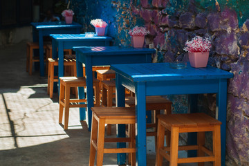 Fototapeta na wymiar Elegant vintage cafe courtyard by the sea with blue tables and orange stools.