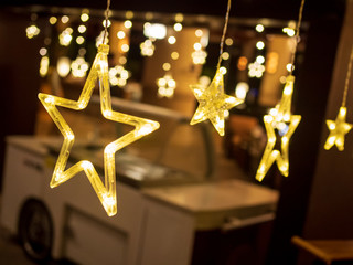 Row of electric lighted stars with warm yellow lights in a against a dark backdrop. Festive /...