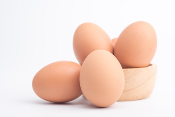 Organic fresh chicken eggs in a brown wooden bowl on a white background