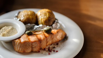 grilled salmon steak and baked potatoes with sauce