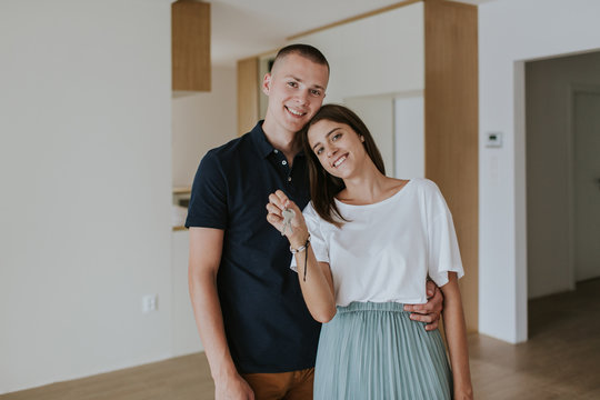 Cheerful young couple in new house holding keys