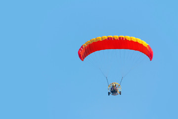 A paraglider with a motor on a sky background