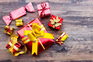 View above brown gift box and red ribbon with tag on wood background with space.