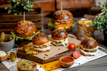 three mini beef burgers and two big burgers served with sauces and pickles