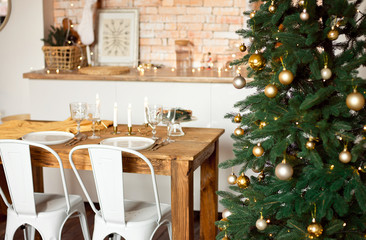 Beautiful festively decorated Scandinavian-style room, a festive table with a table and a Christmas tree with gifts under it.