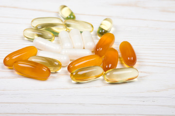 Pile of vitamin pills on a white wooden background