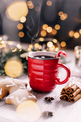 Christmas and new year Red Cup of hot tea or coffee with candy, cinnamon and ginger cookies. Selective focus.