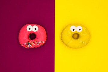 Yellow and red donuts with eyes on color background isolated 