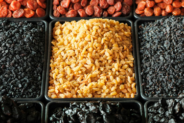 A pile of raisins, various types of dried fruits and other organic products on the counter of the...