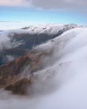 Distant sight view of snowy mountains and fog in late autumn