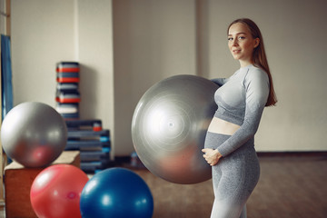 Fototapeta premium Pregnant girl in a gym. Sports girl in a sportswear.