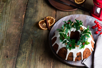 Christmas chocolate cake with white icing and pomegranate kernels on a wooden dark background with red lantern