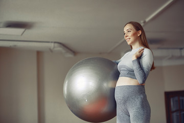 Fototapeta premium Pregnant girl in a gym. Sports girl in a sportswear.