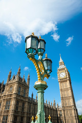 Fototapeta na wymiar Bright blue sky scenic view of Big Ben and the Houses of Parliament with an ornate street lamp on Westminster Bridge in London, UK
