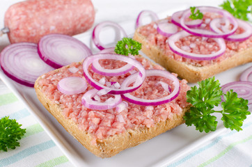 german sandwich with mett ground pork, bun and raw meat with onion and parsley, closeup