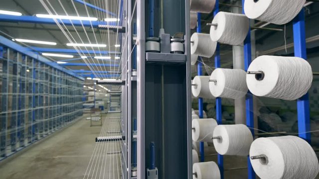 Many clews rotate on a factory rack, spooling with threads. Industrial Textiles Production Line