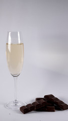 Glass of champagne with chocolate bars on a white background