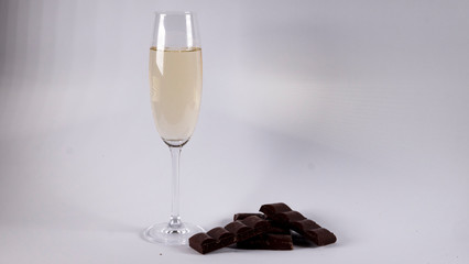 Glass of champagne with chocolate bars on a white background