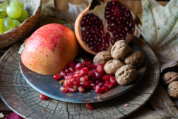 Autumn fruits : grapes, pomegranate and nuts on a background of autumn tree leaves.