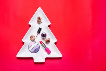 Set of make up accesories on Cristmas tree, copy space, red background